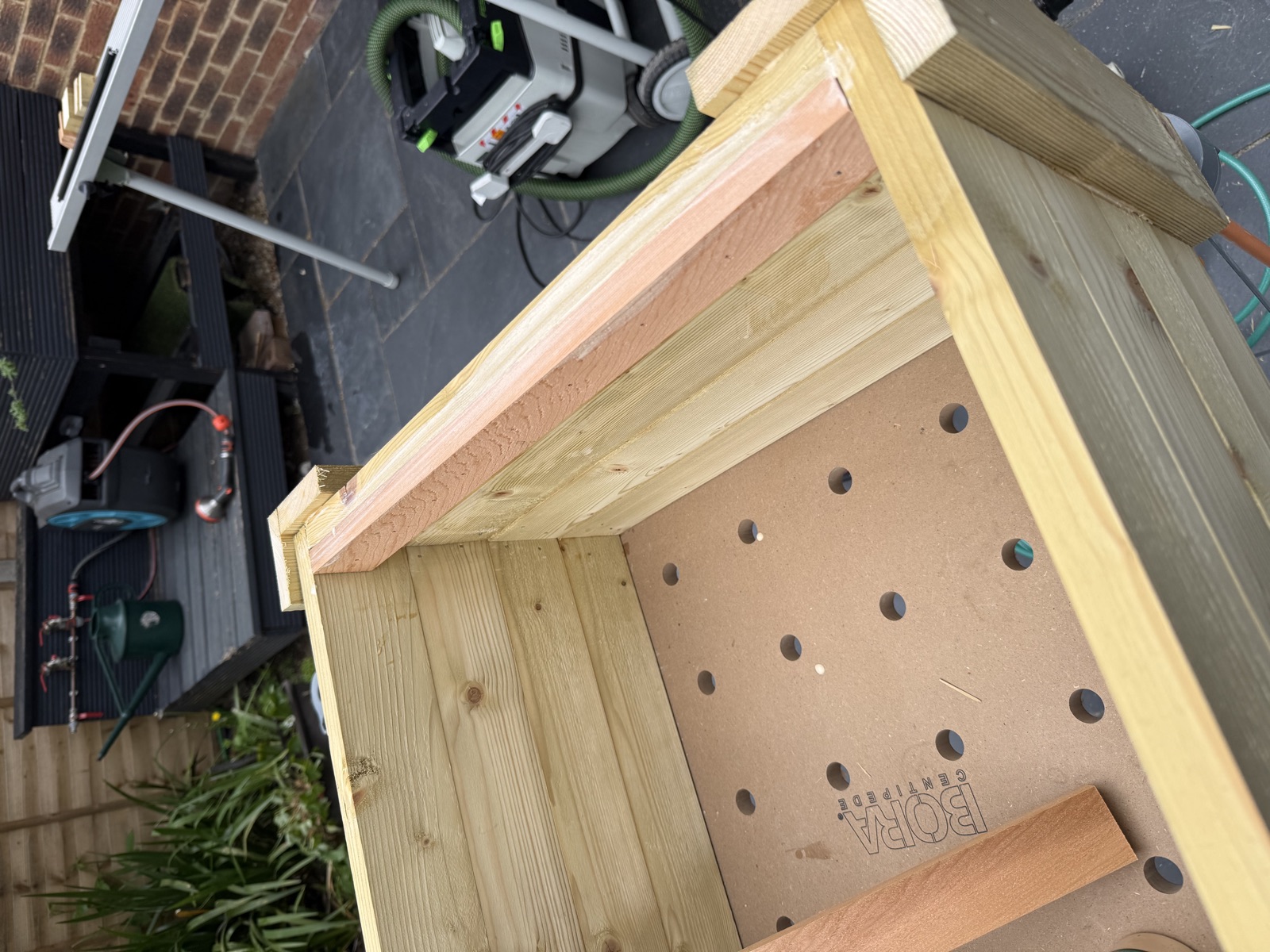 Inner pine frame with L-corner posts assembled, first cedar slat test-fitted